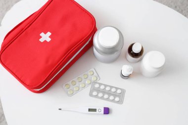 Odadaki masada soğuk algınlığı ilaçları olan ilk yardım çantası.