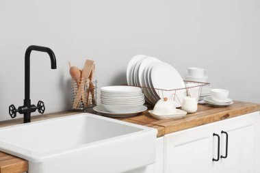 Mutfakta lavabonun yanında temiz beyaz tabakları olan bir tutucu.