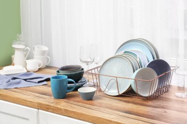 Mutfak penceresinin yanındaki tezgahta temiz mavi tabakları olan tutucu.