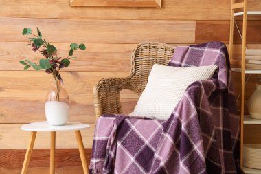 Sehpalı sehpa ve mor ekose hasır koltukta, odasındaki tahta duvarın yanında.