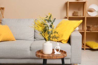 Mimoza çiçekli vazo ve biblo oturma odasındaki masada.