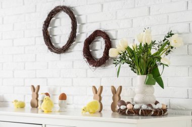 Lale çiçekli masa, boyanmış yumurta, tavşanlar ve beyaz tuğla duvarın yanındaki tavşanlar. Paskalya kutlaması
