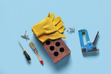 Mavi arka planda tuğla, eldiven ve inşaat araçları