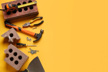 Turuncu arkaplanda tuğla ve inşaat araçları