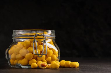 Siyah arka planda peynir kaplı fıstık kavanozu.