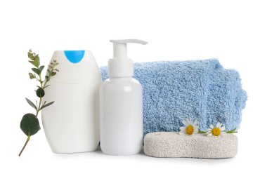 Duş jeli şişeleri, sünger taşı ve beyaz arka planda izole papatya çiçekleri içeren kompozisyon