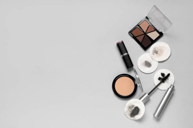 Kirli pamuk pedleri ve gri arka planda farklı kozmetik ürünleri olan kompozisyon