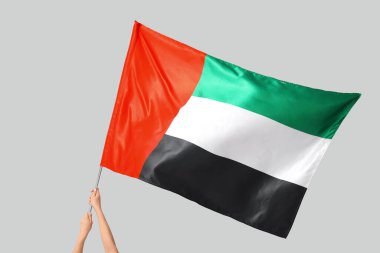 Hafif arkaplanda BAE bayrağı sallayan kadın eller