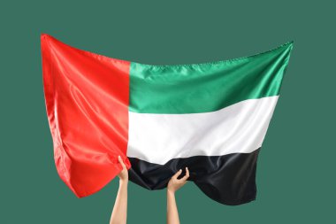 Yeşil arka planda BAE bayrağı taşıyan kadın eller