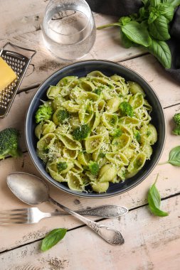 Beyaz ahşap arka planda brokoli ve fesleğen yapraklı enfes conchigile rigate makarnası.