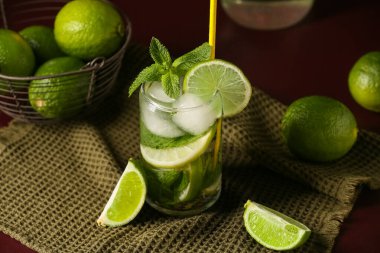 Kırmızı arka planda naneli ve limonlu taze mojito kokteyli, yakın plan.
