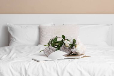 Şakayık çiçekli sepet ve yatağın üzerinde kitaplar, yakın plan.