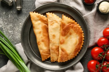 Gri grunge masasında lezzetli chebureks, sebze ve soslu tabak.