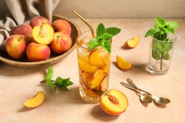 Pembe arka planda bir bardak tatlı şeftalili buzlu çay, yakın plan.