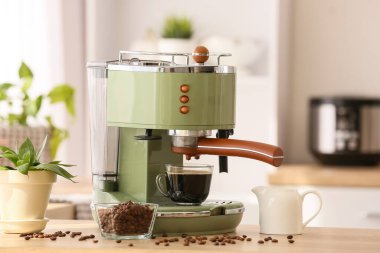 Mutfakta kahve fincanı ve fasulye olan modern kahve makinesi.