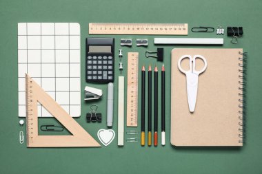 Yeşil arka planda farklı okul malzemeleri.