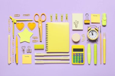 Farklı okul kırtasiye malzemeleri ve eflatun arka planda çalar saat.