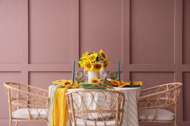 Tabaklar, mumlar ve güzel ayçiçekleri olan zarif bir masa.