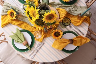 Tabaklarla servis edilen zarif masa, katlanmış peçeteler ve güzel ayçiçekleri, üst manzara.