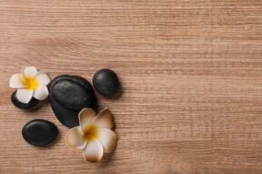 Tahta zemin üzerinde taş ve tesisat çiçekleri olan güzel bir spa kompozisyonu.