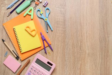 Plastikten yapılmış mektuplar ve ahşap arka planda farklı okul kağıtları.