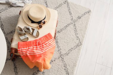 Çocuk yüzme şortu ve plaj aksesuarları ile dolu çanta oturma odasında, üst manzara