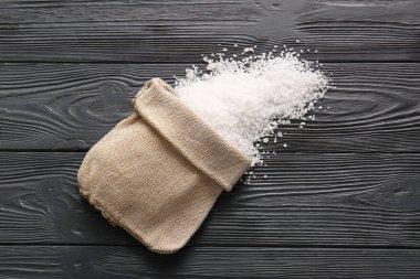 Koyu ahşap arka planda deniz tuzu dolu çuval.