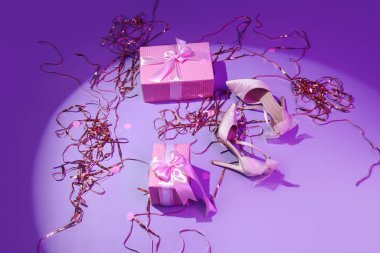Hediye kutularıyla yüksek topuklar ve menekşe arkaplan süsleri.