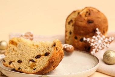 Bir parça Panettone tabağı ve bej arka planda Noel dekoru