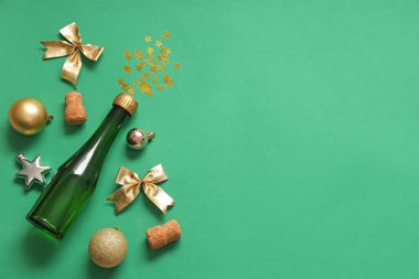 Bir şişe mantarlı şampanya ve yeşil arka planda Noel dekoru.