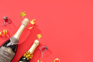 Mantarlı şampanya şişeleri ve kırmızı arka planda konfeti. Noel kutlaması