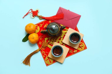 Mandalinalı zarf, çay fincanları ve mavi arka planda Çin sembolleri. Yeni yıl kutlaması