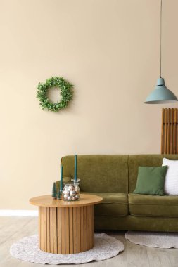 Oturma odasının içinde yeşil kanepe ve sehpanın üzerinde Noel dekoru var.