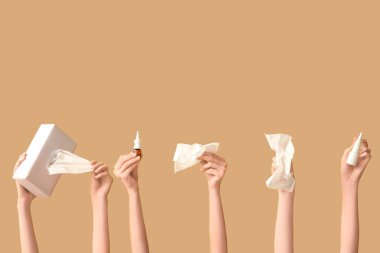 Burun spreyi şişeleri, peçeteler ve bej arka planda peçete kutusu olan kadın elleri.