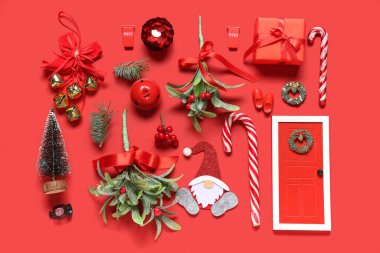 Güzel Noel süsleri, hediye kutusu ve kırmızı arka planda ökseotu dalları olan kompozisyon