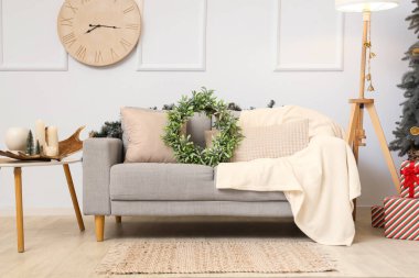 Oturma odasında Noel ökseotu çelengi olan rahat bir kanepe.