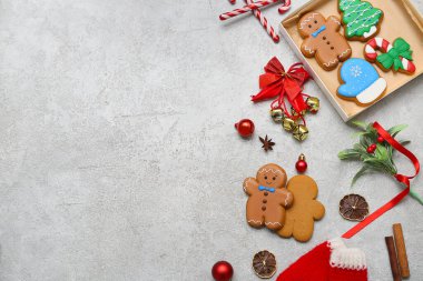 İçinde zencefilli kurabiye, kurutulmuş portakal dilimleri ve gri arka planda Noel süslemeleri olan hediye kutusu.