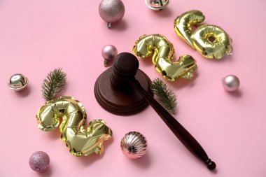 Hakimin tokmağı ve pembe arka planda Noel topları olan 2025 'i düşün.