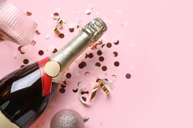 Bir şişe şampanya ve pembe arka planda konfeti. Yeni yıl kutlaması