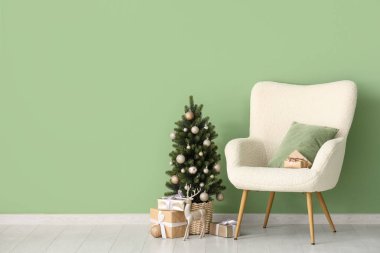 Koltuk ve Noel ağacı, yeşil duvarın yanında hediyeler.