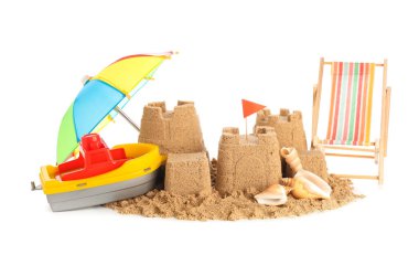 Beyaz arka planda kumdan kale, mini şezlong, şemsiye ve oyuncak tekne.