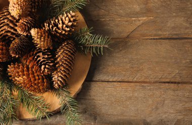 Ahşap zemin üzerinde çam kozalakları ve köknar dalları olan tahta.