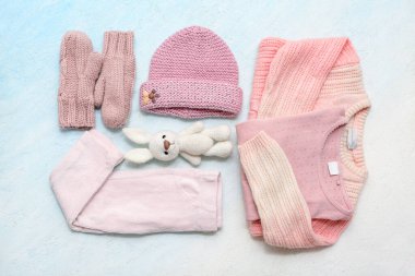 Şık çocuk kazakları, eldivenleri, pantolonu, oyuncağı ve şapkası mavi grunge arka planda.