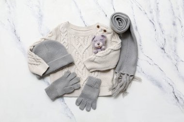 Şık çocuk süveteri, eşarp, şapka, eldiven ve mermer arka planda oyuncak