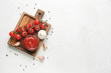 Ahşap tepside bir kase lezzetli ketçap ve beyaz grunge arka planda malzemeler