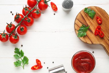 Lezzetli ketçap kasesinden yapılmış çerçeve ve beyaz ahşap arka planda malzemeler