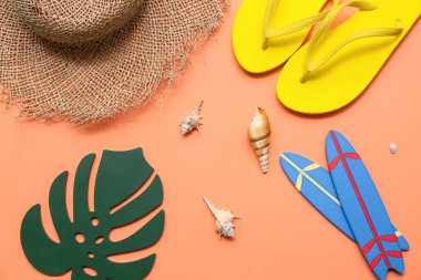 Terlik, deniz kabuğu ve turuncu arka planda hasır şapkalı mini sörf tahtaları. Yaz konsepti