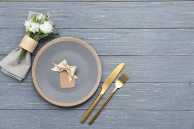 Gri ahşap arka planda yay ve güzel çiçeklerle süslü bir masa.