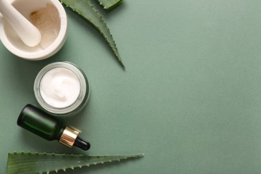 Yeşil zemin üzerinde aloe vera yaprakları olan farklı kozmetik ürünleri