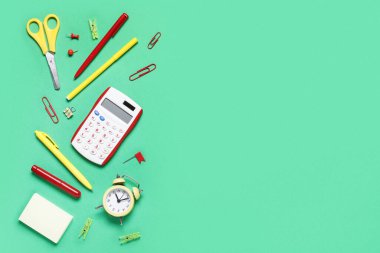 Alarm saati ve yeşil arka planda farklı okul kırtasiyesi olan kompozisyon